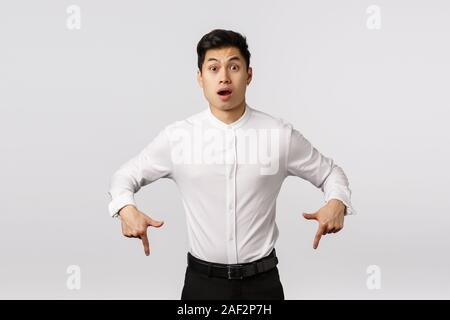 Freak Out, alarmiert und asiatischen hübscher Kerl im Kragen Hemd, Hosen überrascht, schockiert, der nach unten zeigt, schnappte erstaunt und sprachlos, sagen, wow, hören Stockfoto
