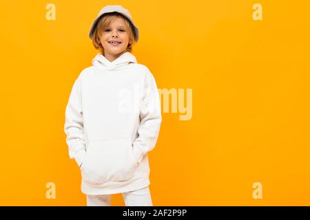 Europäische Junge mit einem Panama in einem hellen hoodie auf orangem Hintergrund Stockfoto