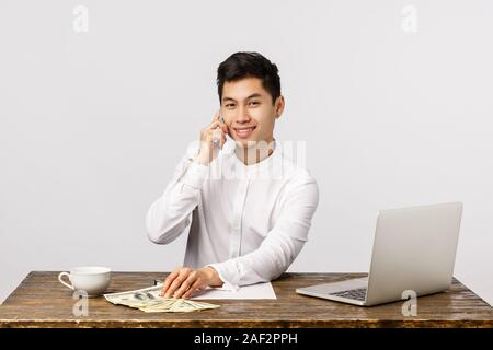 Hallo, wie kann ich Ihnen helfen. Attraktive und erfolgreiche Geschäftsmann starten eigene Firma Business, Büro Tisch mit Laptop sitzen, Kaffee trinken suchen Stockfoto