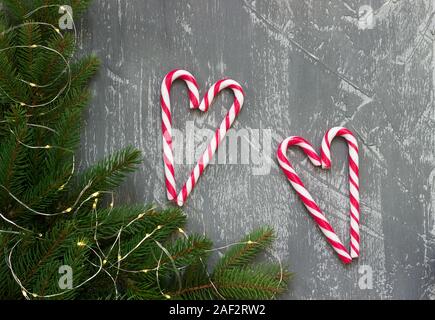 Winter Hintergrund mit Tannenzweigen, Girlande und Zuckerrüben auf einem grauen Betonhintergrund. Grußkarte. Stockfoto