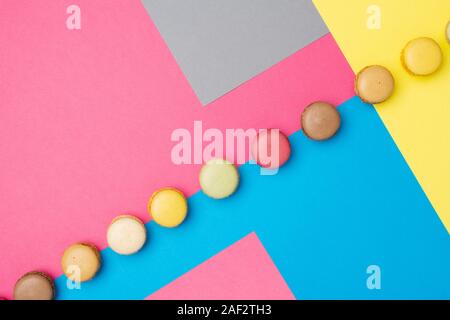 Klassische französische Dessert. Bunte macarons auf kreative Rosa Grau Blau Gelb Hintergrund angeordnet, selektiver Fokus Stockfoto