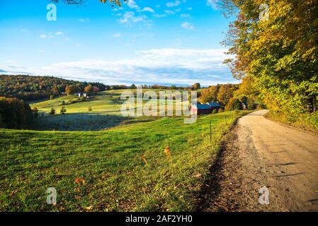 Rolling herbstliche Landschaft bei Sonnenaufgang mit einem Schotterweg im Vordergrund. Atemberaubende Farben des Herbstes. Stockfoto