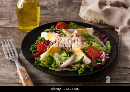Salat mit Thunfisch, Ei und Gemüse auf hölzernen Tisch Stockfoto