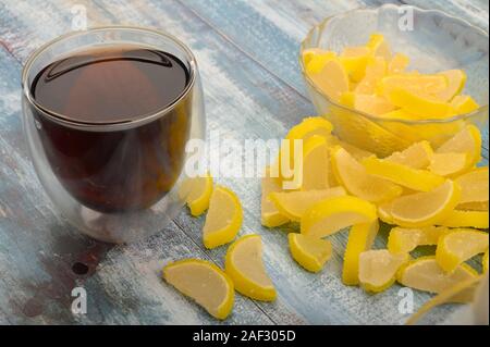 Marmelade Zitronenscheiben und einem Glas schwarzen Tee auf einem hölzernen Hintergrund. Süße Nachspeise. Nahaufnahme Stockfoto