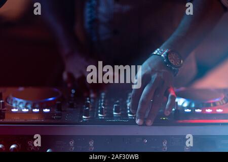Club-DJ spielt Musik auf der Bühne im Nachtclub. Hand der disc jockey Sound Track Lautstärke einstellen. Professionelle Audiogeräte auf Music Festival Stockfoto