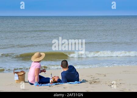 Paar am Strand, mit Blick auf das Meer, mit einem Picknick Stockfoto