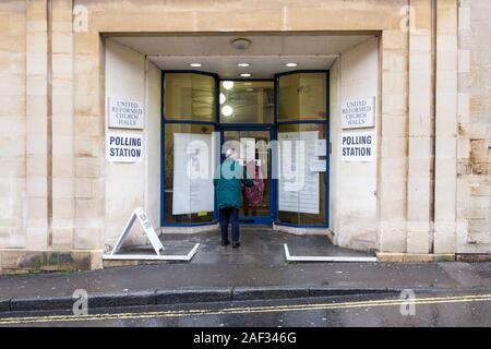 Badewanne, Somerset, UK. 12 Dez, 2019. Eine Frau trotzen dem Regen und gehen in die 2019 Bundestagswahl zur Abstimmung wird dargestellt, wie Sie dem Wahllokal, die in einer Kirche Halle in der Mitte der Badewanne gesetzt wurde. Credit: Lynchpics/Alamy leben Nachrichten Stockfoto