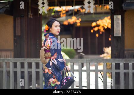 Geishas Mädchen mit japanischen kimono unter roten Holz- Tori Gate bei Fushimi Inari Schrein in Kyoto, Kimono ist ein traditionelles japanisches Gewand. Das Wort " Stockfoto