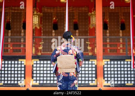 Geishas Mädchen mit japanischen kimono unter roten Holz- Tori Gate bei Fushimi Inari Schrein in Kyoto, Kimono ist ein traditionelles japanisches Gewand. Das Wort " Stockfoto