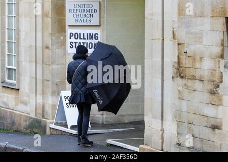 Badewanne, Somerset, UK. 12 Dez, 2019. Eine Frau trotzen dem Regen und gehen in die 2019 Bundestagswahl zur Abstimmung wird dargestellt, wie Sie dem Wahllokal, die in einer Kirche Halle in der Mitte der Badewanne gesetzt wurde. Credit: Lynchpics/Alamy leben Nachrichten Stockfoto