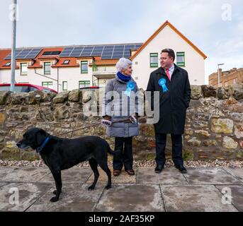 Gullane, Bowling Club, East Lothian, Schottland, Vereinigtes Königreich, 12. Dezember 2019. Britischen Wahlen: einen Schottischen Konservativen Partei Aktivist mit einem Labrador Hund an der Leine & Craig Hoy, der Schottischen Konservativen Kandidaten an der örtlichen Wahllokal Stockfoto