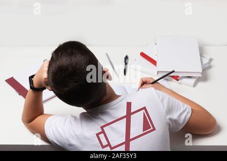 Gelangweilt und müde Junge Hausaufgaben auf weißem Schreibtisch in seinem Zimmer. Schüler Probleme Konzept. ISo Stockfoto