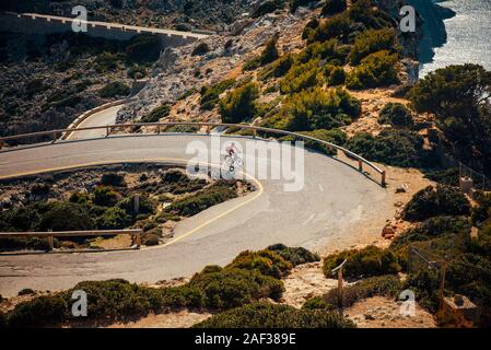 Radfahrer auf der Straße in der mediterranen Landschaft. Farbe orange Filter Stockfoto