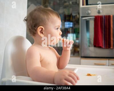 1 Jahr alte Hündin Baby sitzt auf einem hohen Stuhl warten auf Ihre Mahlzeit Stockfoto