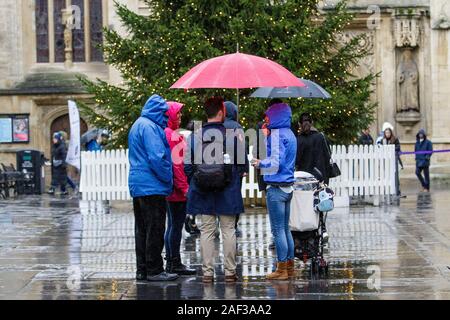 Badewanne, Somerset, UK. 12 Dez, 2019. Touristen unter Schutz unter Sonnenschirme sind vor der Abtei von Bath als heftiger Regenschauer ihren Weg in ganz Großbritannien. Credit: Lynchpics/Alamy leben Nachrichten Stockfoto