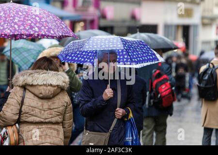 Badewanne, Somerset, UK. 12 Dez, 2019. Leute, Shopping in Bath, Somerset abgebildet Tierheim unter Sonnenschirmen als heftiger Regenschauer ihren Weg in ganz Großbritannien. Credit: Lynchpics/Alamy leben Nachrichten Stockfoto