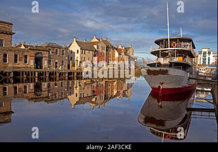 Leith, Edinburgh, Schottland, Großbritannien. 12. Dezember 2019. Bild, Wasser des Leith vom Ufer über die Benutzerdefinierte Wharf in Sonnenschein an einem Winter' Tag mit einer Temperatur von 5 Grad gebadet, wenig oder kein Wind, die fast perfekte Reflexionen des Ozeans Nebel, die gerade renoviert wird und die Gebäude an der Wharf. Stockfoto