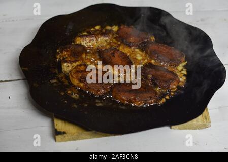 Die koteletts Pan im Feuer gebraten. Pan ist auch das Kochen Fleisch. Schwein Stücke von Fleisch sind auf ein Lagerfeuer auf einer Disc aus einer Egge gekocht. Brocken Fleisch gebraten Stockfoto