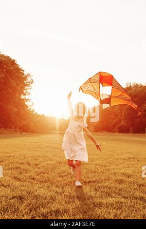 Urlaub im Dorf. Glückliches Mädchen in weißen Kleidern viel Spaß mit Kite im Feld. Schöne Natur Stockfoto