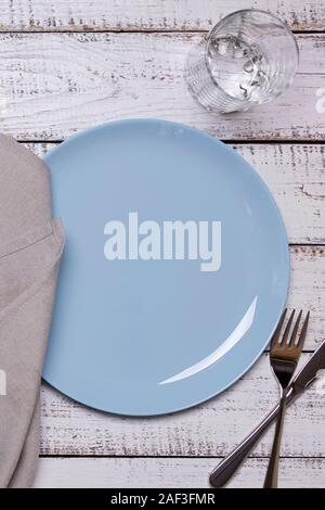 Blue Platten, Servietten und Besteck auf einer alten weißen Holz- Hintergrund. Blick von oben. Stockfoto