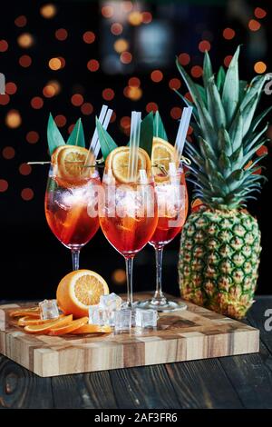 Eine große pineaple und Orangen. Cocktails bereit ist. Auf dem Holztisch in der Night Club. Schöne Beleuchtung Stockfoto