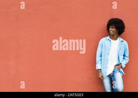 African American hipster junge Erwachsene auf die rote Wand mit Kopie Raum im Freien im Sommer Stockfoto