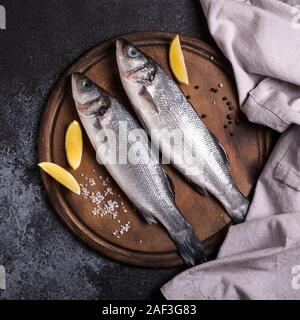 Frische rohe ganze Seebarsch. Raw Wolfsbarsch Fisch mit Gewürzen und Kräutern Zutaten. Ansicht von oben mit der Kopie. Stockfoto