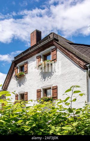 Teil eines alten Bauernhauses mit Blumenkästen an den Fenstern Stockfoto