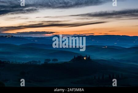 Typische hügelige Toskanische Landschaft im Val d'Orcia, der Bauernhof Podere Belvedere auf einem kleinen Hügel und Nebel in den Tälern, bei Sonnenaufgang Stockfoto