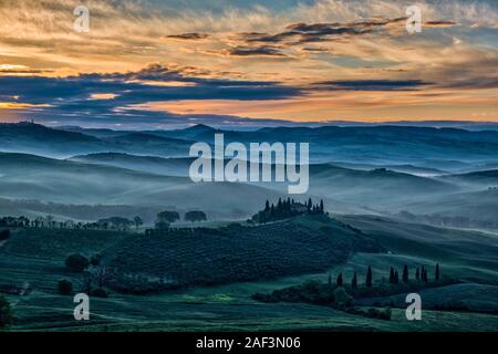 Typische hügelige Toskanische Landschaft im Val d'Orcia, der Bauernhof Podere Belvedere auf einem kleinen Hügel und Nebel in den Tälern, bei Sonnenaufgang Stockfoto