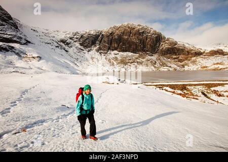 Frau Hill Wanderer durch eine gefrorene scheut Tarn in die saisonabhängige, Lake District, Großbritannien Stockfoto