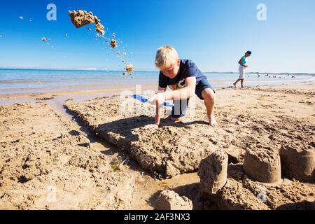 Ein Junge, bauen eine Sandburg am Strand von Bamburgh, Northumberland, UK. Stockfoto