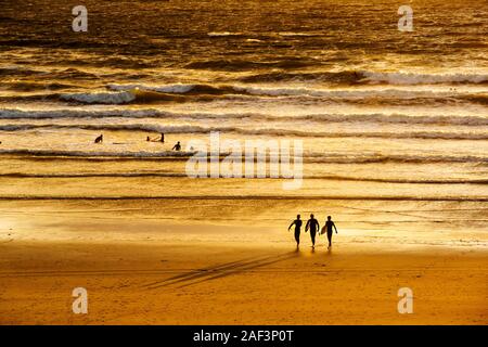 Surfer am Polzeath bei Sonnenuntergang, Cornwall, UK. Stockfoto