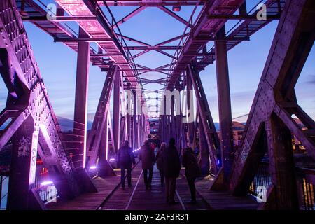 12 Dezember 2019, Sachsen-Anhalt, Magdeburg: Besucher gehen über dem ehemaligen Hubbrücke, die mit farbigen Strahlern beleuchtet wird. Auf der einen Seite der Brücke, ein weiterer Weihnachtsmarkt eröffnet am Nachmittag und dauert bis zum 15. Dezember 2019. Foto: Klaus-Dietmar Gabbert/dpa-Zentralbild/ZB Stockfoto