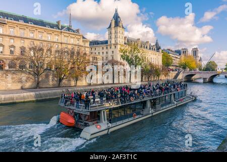 Paris, Frankreich - 7 November 2019: Ein Fluss Schiff segeln entlang der Seine, neben dem Gericht. Saint-Michele Brücke und dahinter, der Notre Da Stockfoto