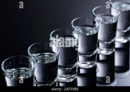 Gläser Wodka auf einem schwarzen reflektierenden Hintergrund. Selektive konzentrieren. Stockfoto