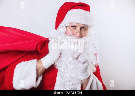 Santa Claus mit großen Sack voll Geschenke auf weißem Hintergrund. Stockfoto