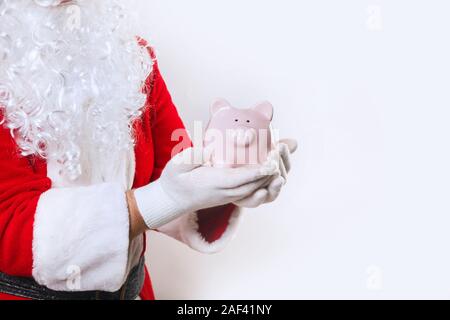 Piggy Bank in den Händen von Santa Claus auf einem weißen Hintergrund Stockfoto