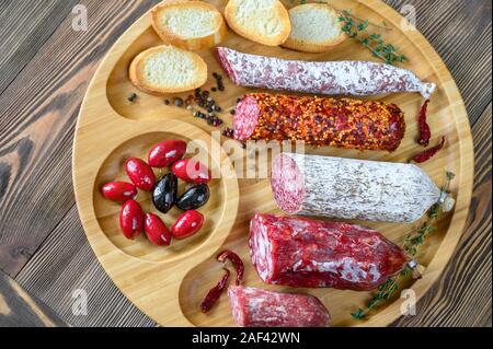 Sortiment von Salami mit Häppchen auf hölzernen Hintergrund: Ansicht von oben Stockfoto
