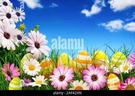 Frühling Blumen und fröhlich bunte Ostereier mit einem klaren, blauen Himmel im Hintergrund Stockfoto