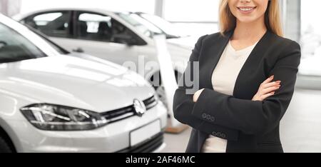 Professionelle Autoverkäufer in Schwarz smart Anzug mit verschränkten Armen vor der neuen Autos im Showroom. Angenehme weibliche Autohändler helfen und beraten Kunden und Käufern in Auto Salon. Stockfoto