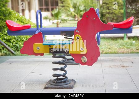 Auf Kind Spielplatz im Park Wippe. childs Ausritt mit dem Pferd in den Spielplatz. Schwingen auf einer metallspirale. Feder Pferd auf dem Spielplatz. Stockfoto