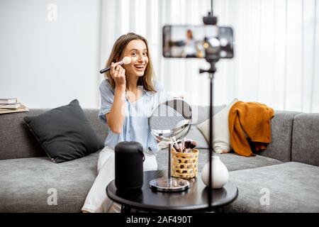 Junge Frau Aufzeichnung auf einem Smartphone Ihr vlog über Kosmetik, zeigen und demonstrieren Make-up. Influencer Marketing in social media Konzept Stockfoto