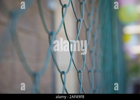 Detail von einem Zaun mit abstrakten Hintergrund. close up Stahl Zaun gegen grünes Feld: enge Tiefenschärfe. Kühlergrill und der Hintergrund verschwommen. Blau Metall Stockfoto
