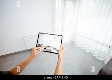 Neue Möbel auf einem digitalen Tablet in den leeren Innenraum, schauen, wie es aussieht, bevor Sie kaufen. Konzept der Augmented Reality in Design und Retail Business Stockfoto