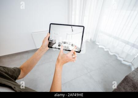 Neue Möbel auf einem digitalen Tablet in den leeren Innenraum, schauen, wie es aussieht, bevor Sie kaufen. Konzept der Augmented Reality in Design und Retail Business Stockfoto