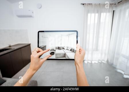 Neue Möbel auf einem digitalen Tablet in den leeren Innenraum, schauen, wie es aussieht, bevor Sie kaufen. Konzept der Augmented Reality in Design und Retail Business Stockfoto