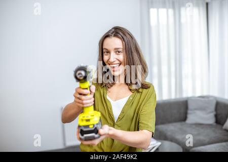 Portrait einer jungen und glücklich handywoman mit Akkuschrauber zu Hause. Konzept eines einfachen Haushalt arbeiten mit modernen Werkzeugen Stockfoto