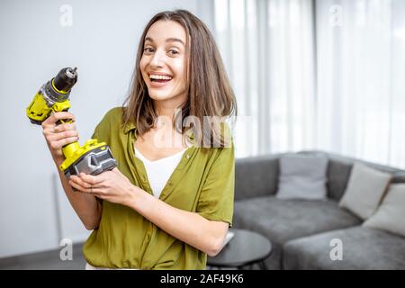 Portrait einer jungen und glücklich handywoman mit Akkuschrauber zu Hause. Konzept eines einfachen Haushalt arbeiten mit modernen Werkzeugen Stockfoto