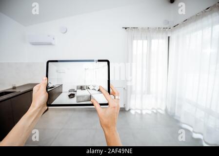 Neue Möbel auf einem digitalen Tablet in den leeren Innenraum, schauen, wie es aussieht, bevor Sie kaufen. Konzept der Augmented Reality in Design und Retail Business Stockfoto